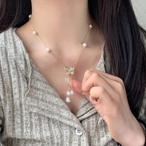Elegant gold butterfly necklace with white pearls and sparkling zircons worn by a model