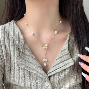Elegant gold butterfly necklace with cubic zirconia and freshwater pearl tassels on model