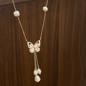 Detail of elegant gold butterfly necklace with crystal inlay and pearl tassels on wood