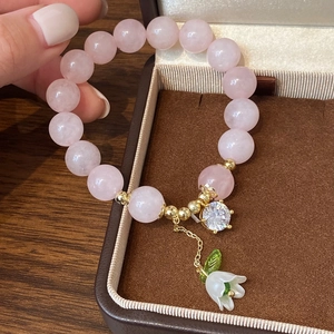 Pink strawberry quartz beaded bracelet with white lily of the valley flower charm and gold accents