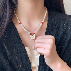 Collier de perles élégant avec perles rouges et pendentif papillon en zircon sur un mannequin