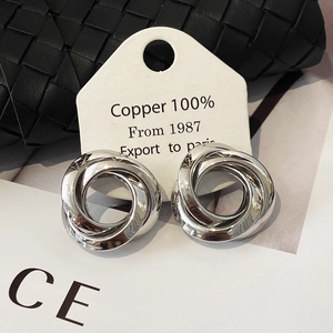 Macro detail of silver interlocking circular earrings on textured background with tag
