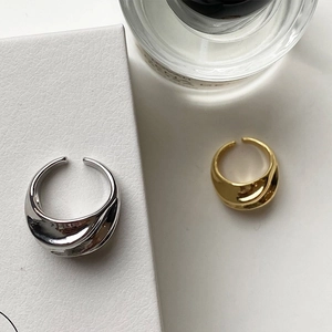 Detailed macro shot of minimalist wave-shaped open rings in gold and silver finishes