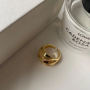 Detail of golden pleated ring featuring a wavy 3D textured finish and adjustable opening