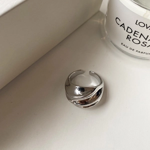 Detailed view of silver pleated irregular wavy ring on a minimalist aesthetic surface