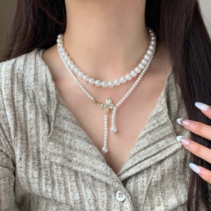 Double-layered pearl necklace with a sparkling butterfly pendant and elegant tassels