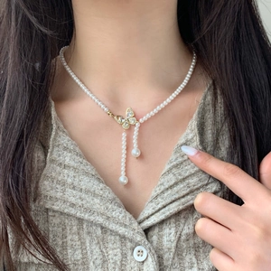Elegant pearl necklace featuring a gold zircon butterfly pendant and tassel drops on model