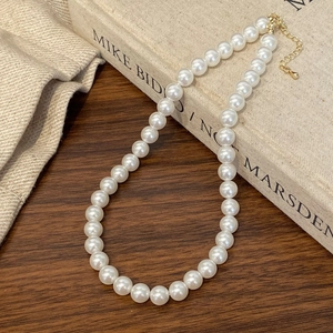Detail of white round pearls on a butterfly necklace with golden extender chain