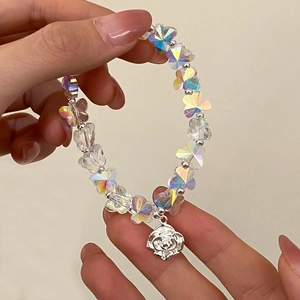 Bracelet élégant en cristal avec perles papillon et pendentif rose porté au poignet