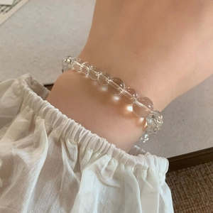 Close-up of white crystal bead bracelet with geometric zircon pendant on female wrist