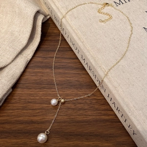 Detailed close-up of a Y-shaped gold pearl necklace with adjustable lobster clasp closure