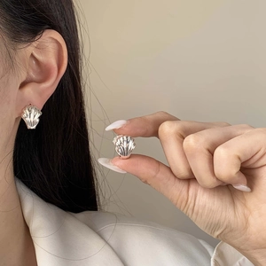 Detail of 18K gold plated double wing earrings showing texture and size on model's ear