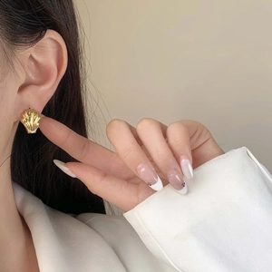 Close-up of elegant 18K gold plated shell earrings worn by a model in soft lighting