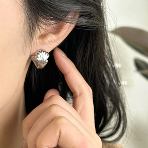 Silver double-layer wing stud earrings with elegant shell texture on a model's ear