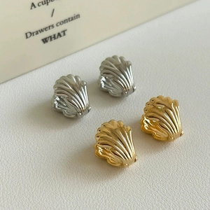 Macro view of gold and silver wing-shaped textured earrings on white leather