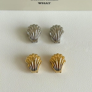 Detail of shell-shaped double-layered wing earrings in gold and silver finish