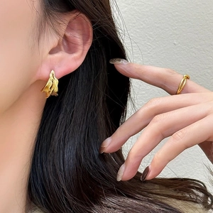 Detail von unregelmäßigen vergoldeten C-Ohrringen und minimalistischem Ring am Modell