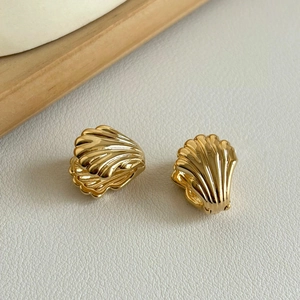 Macro shot of 18K gold-plated double-layered shell earrings with polished textures