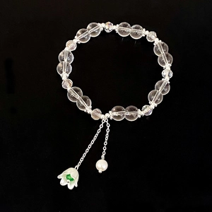 Elegante bracciale di cristallo trasparente con ciondoli a fiore e perla su sfondo nero