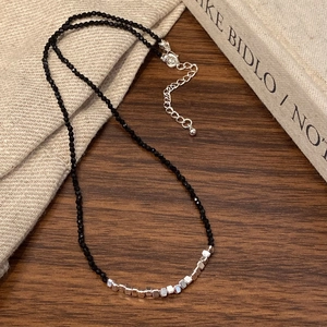 Detail of a black beaded choker with geometric silver beads on a vintage book background