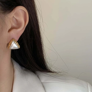 Elegant gold geometric triangle earrings with pearl center inlay on a model