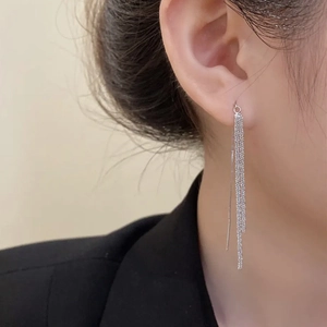 Gros plan de boucles d'oreilles longues à pampilles argentées portées par un mannequin