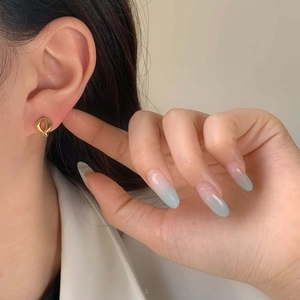 Minimalist geometric hollow gold stud earrings with polished finish shown on a model