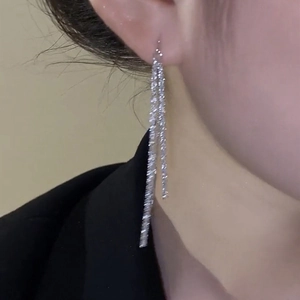Gros plan d'élégantes boucles d'oreilles pendantes en argent portées par un mannequin