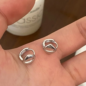 Detail shot of small silver geometric hoop earrings held in hand for size visualization