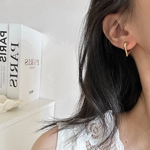 Polished gold heart shaped earrings on a female model for a minimalist jewelry aesthetic