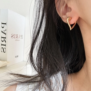 Detailed close-up of a high-polish gold heart-shaped hoop earring worn by a model