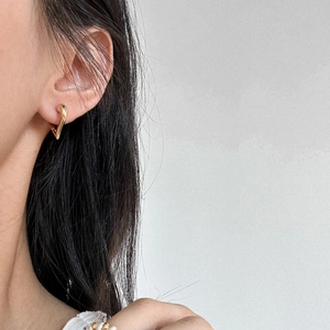 Close-up of heart-shaped gold-plated hoop earrings with a polished wavy texture