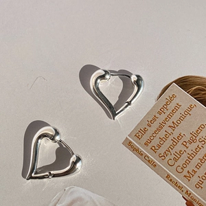 Close-up of chunky liquid silver heart earrings with a polished metallic finish and soft curves