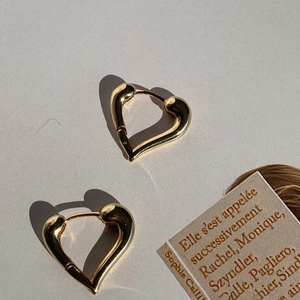 Detailed view of heart-shaped gold plated earrings with a polished wavy metallic finish