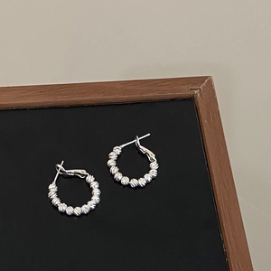 Close-up of silver hoop earrings featuring textured beads and a polished metallic finish