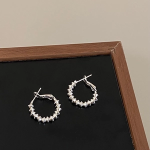 Close-up of silver beaded hoop earrings with textured finish on black display board