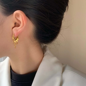 Pendientes de aro dorados con borlas y lentejuelas en una modelo con estilo retro
