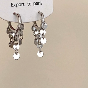 Detalle de pendientes de aro plateados con borlas de lentejuelas pulidas en tarjeta blanca