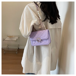 Detail of light purple quilted bag with pearl chain and elegant metal closure
