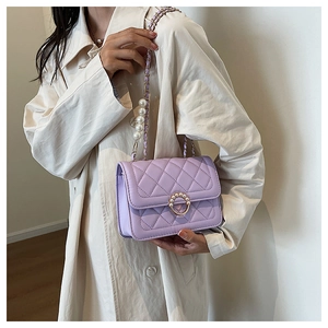 Close-up of lavender quilted bag with pearl-inlaid gold buckle and chain strap