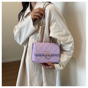 Detail of purple quilted shoulder bag with pearl accents and metal ring buckle