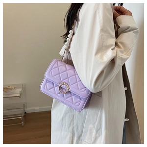 Detail of lavender quilted crossbody bag featuring elegant pearl buckle and pearl chain strap