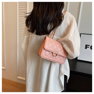Pink quilted crossbody bag with pearl buckle and metal chain strap shown on a model
