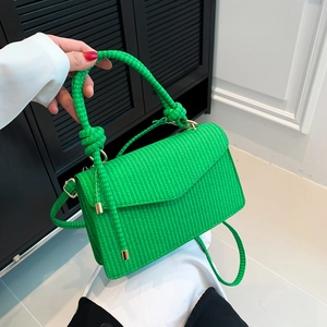 Minimalist grass green woven handbag with a knotted handle and gold hardware on shoulder strap