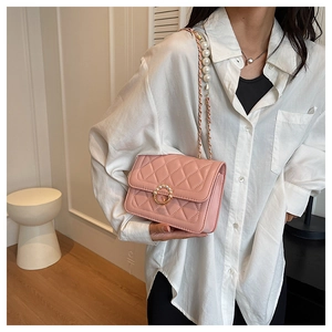 Detail view of pink quilted handbag featuring elegant pearl strap and gold ring buckle