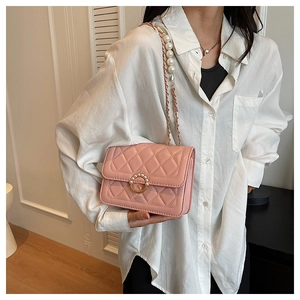 Quilted crossbody bag with pearl strap and circular clasp shown on a model