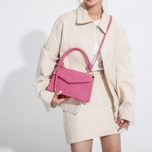 Hot pink woven handbag with top handle and shoulder strap shown on a model for size comparison