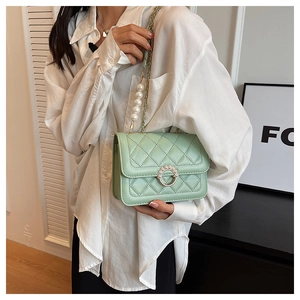 Detail of mint green quilted crossbody bag with pearl strap and circular pearl clasp