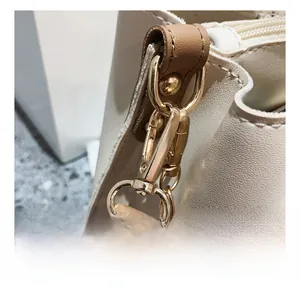 Close-up of golden metal hooks and premium stitching on a beige leather handbag