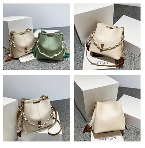 Detail view of bucket bag with silk scarf handle and metal clasp in green and cream